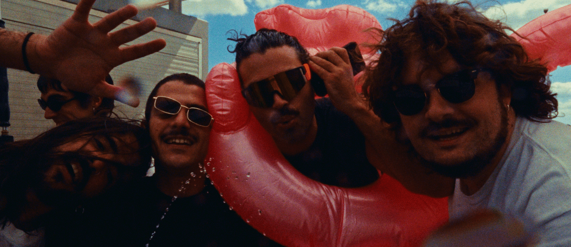 Los miembros de Puño Dragón con gafas de sol y un flotador rosa en el videoclip de Fogonazo Rápido